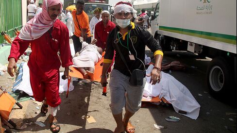 Saudi emergency personnel and Hajj pilgrims carry a wounded person at the site where at least 450 were killed and hundreds wounded in a stampede in Mina, near the holy city of Mecca, at the annual hajj in Saudi Arabia, on Sept. 24, 2015.