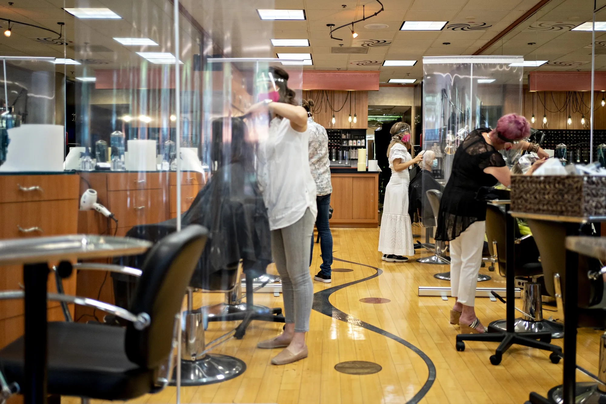 Stylists work behind plastic dividers at a hair salon in Arlington, Virginia.