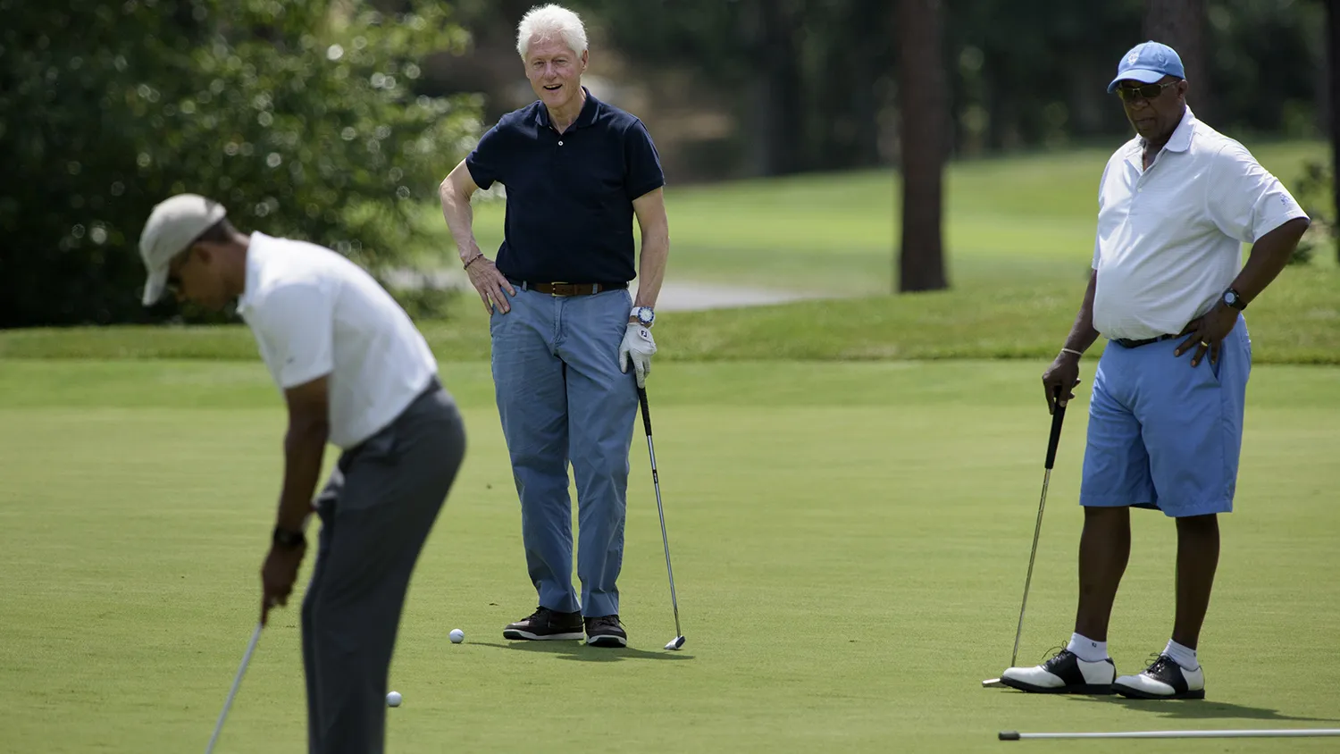 Former US President Bill Clinton (C) and Ron Kirk (R) watch as US President Barack Obama putts while golfing at Farm Neck Golf Club August 15, 2015 in Oak Bluffs, Massachusetts on Martha's Vineyard.
