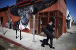 A mariachi musician walks past a mural in the Boyle Heights area of Los Angeles.