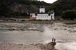 Visitors walk along exposed rock on the shoreline of the River Rhine in Kaub, Germany.