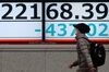 A pedestrian walks past an electronic quotation board displaying share prices of the Nikkei 225 Index in Tokyo on February 26, 2020. 