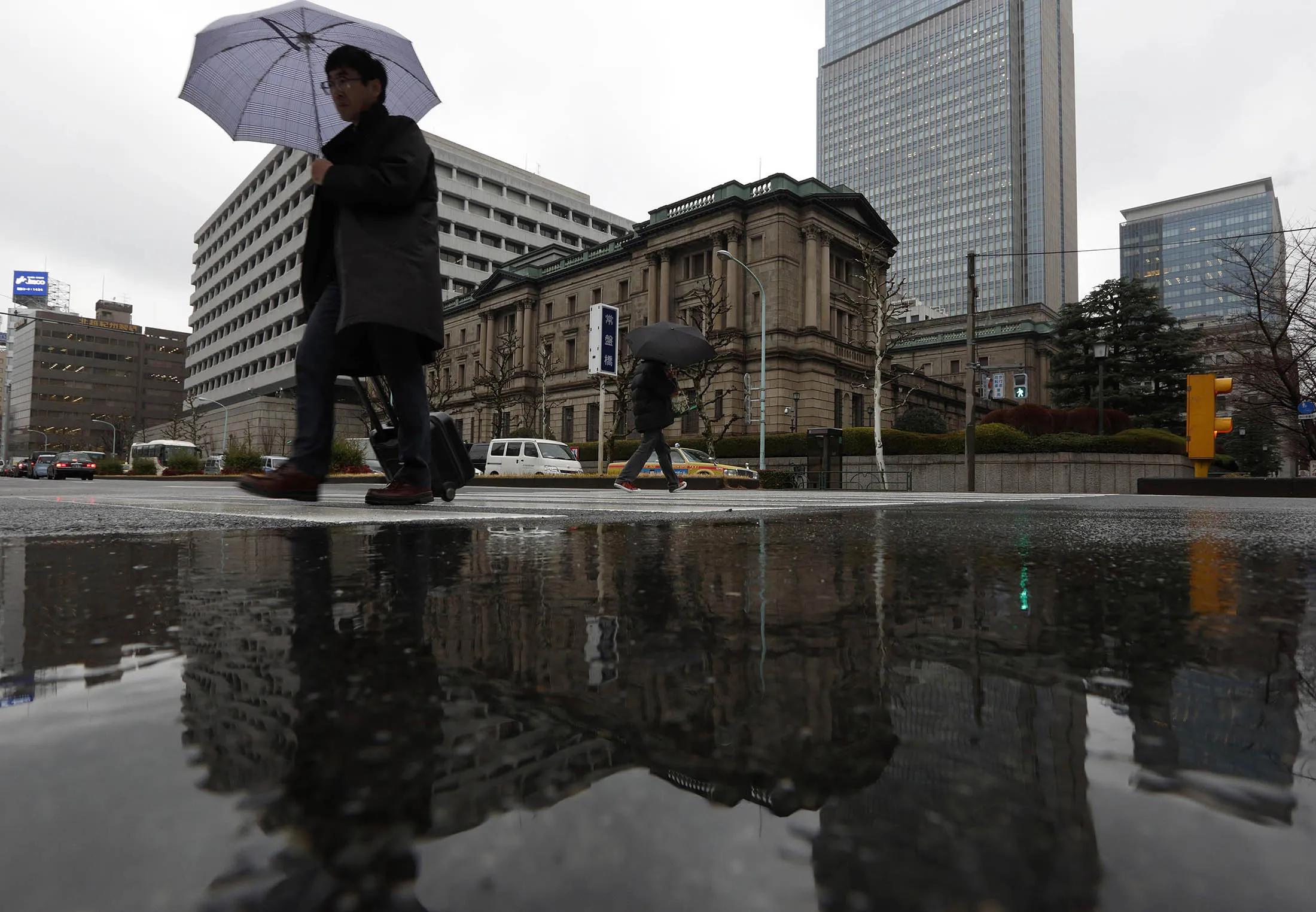 Pedestrians walk past the Bank of Japan headquarters in Tokyo.
