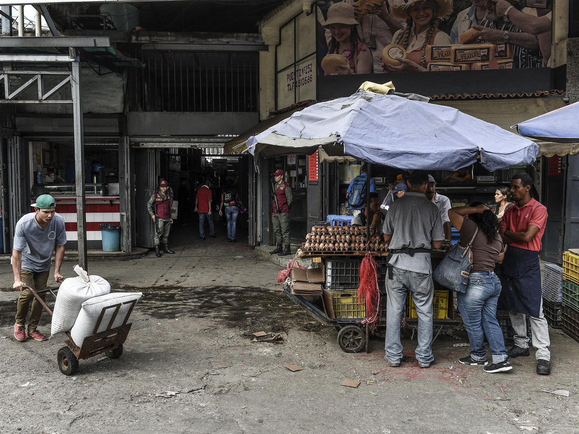 Members of the Bolivarian National Guard&nbsp;stand guard as shoppers browse goods at the Municipal Market of Quinta Crespo in Caracas, Venezuela.