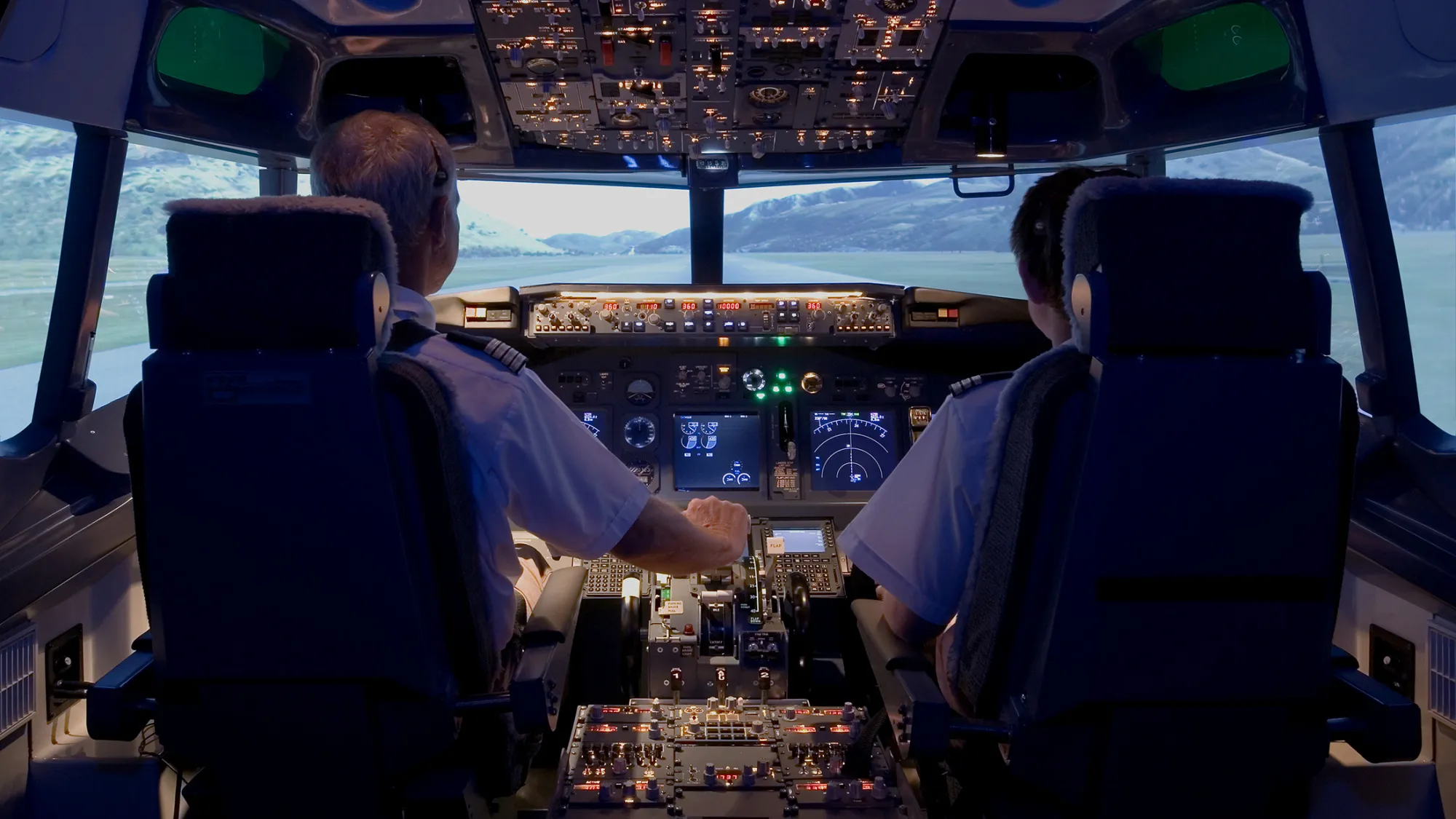 Pilots sitting in flight simulator, rear view
