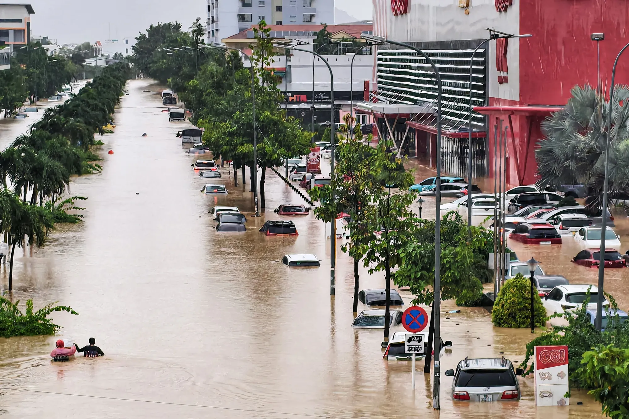 Pessoas caminham em meio às águas da enchente perto de veículos inundados em Nha Trang, na província costeira de Khanh Hoa, no Vietnã, em 20 de novembro.