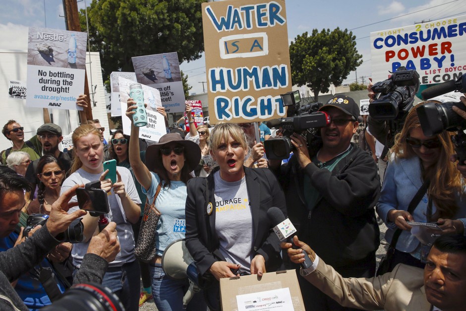 Laura Leavitt of the Courage Campaign, center, carries a box of petitions during a march against Nestle bottling water during the California drought, outside a Nestle Arrowhead water-bottling plant in Los Angeles.
