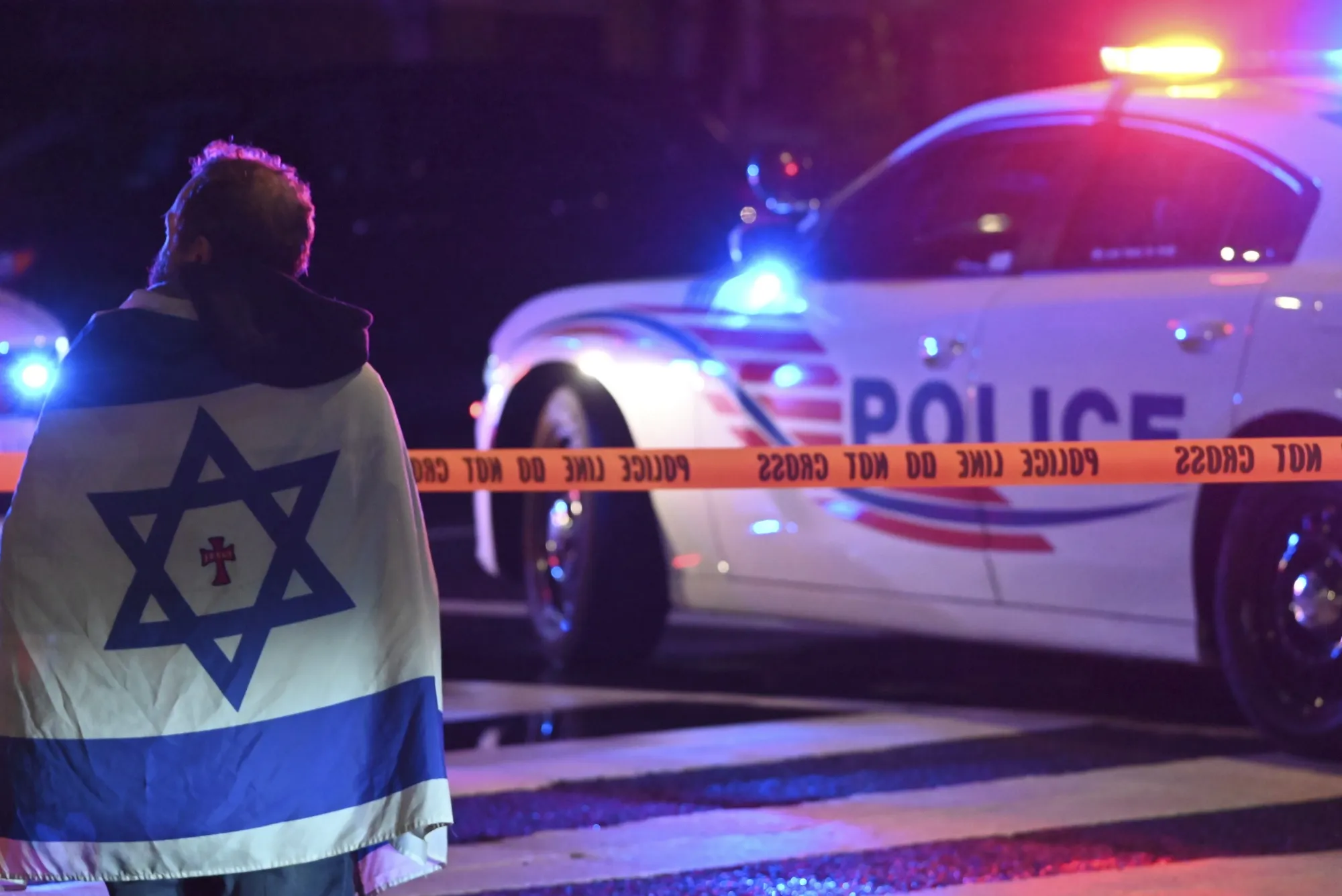 An onlooker watches as police officers secure the area outside the Capital Jewish Museum following a shooting that left two people dead in Washington, DC, on May 22.