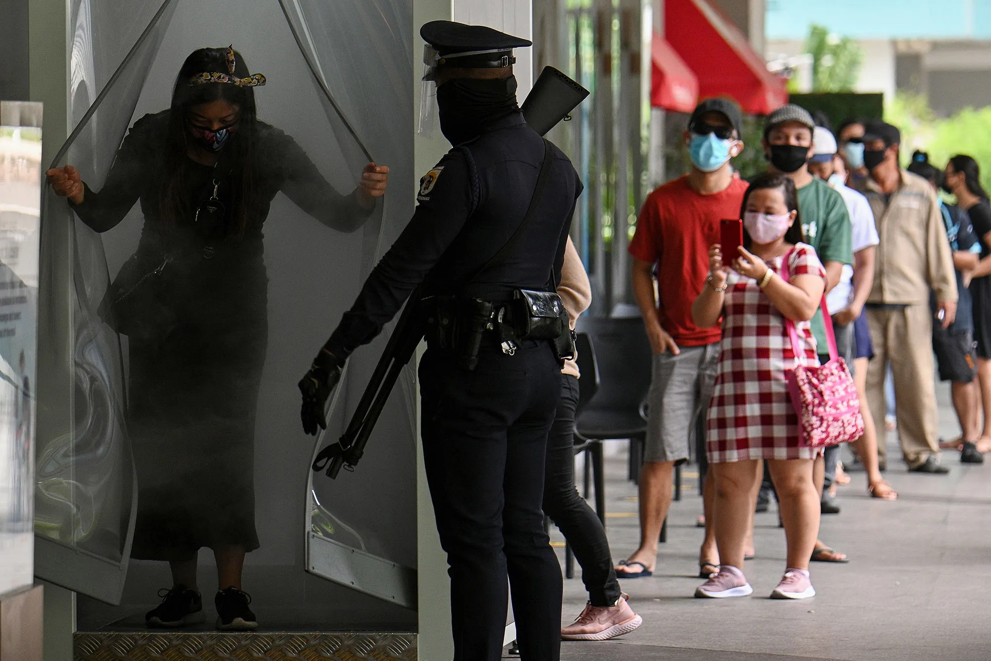 A security guard&nbsp;watches as a shopper exits from a disinfection channel at the entrance of a shopping mall&nbsp;in Manila on May 16.