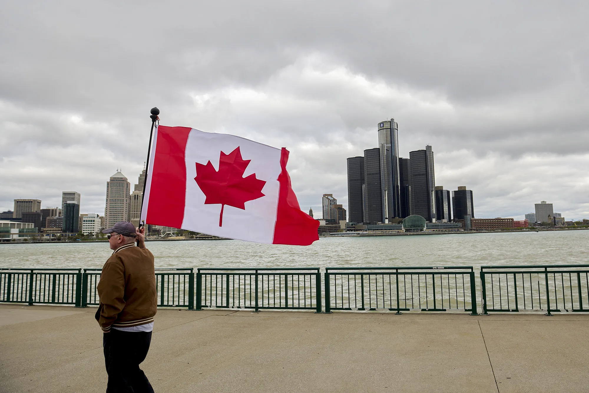 A man flies the Canadian flag on&nbsp;the Detroit River waterfront during a rally in Windsor, Ontario