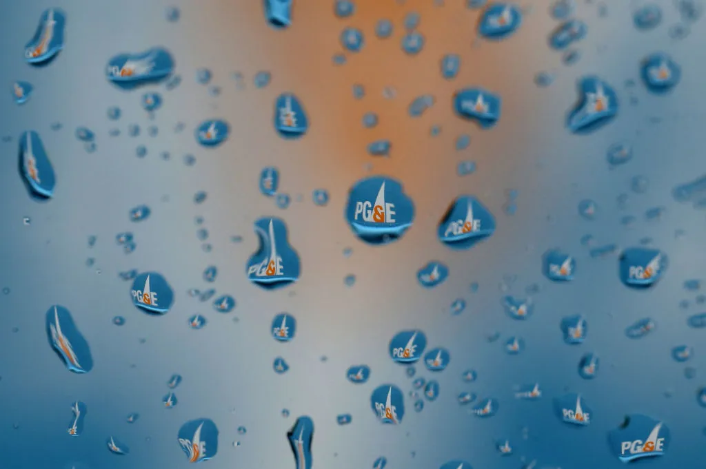 The Pacific Gas &amp; Electric (PG&amp;E) logo on a truck is visible through raindrops on a window.