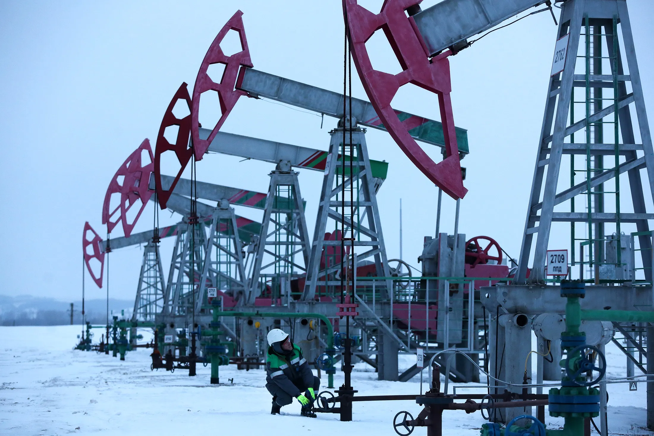 A worker makes adjustments to an oil pumping jack outside the village of Nikolo-Beryozovka near Neftekamsk, Russia.
