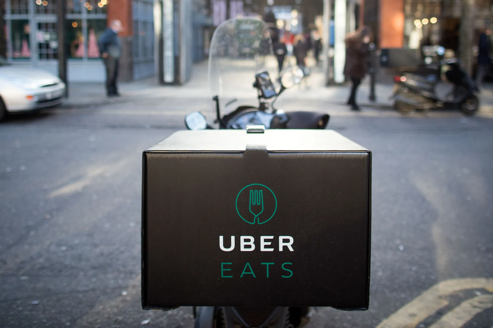 An UberEats branded box sits on a motor scooter.