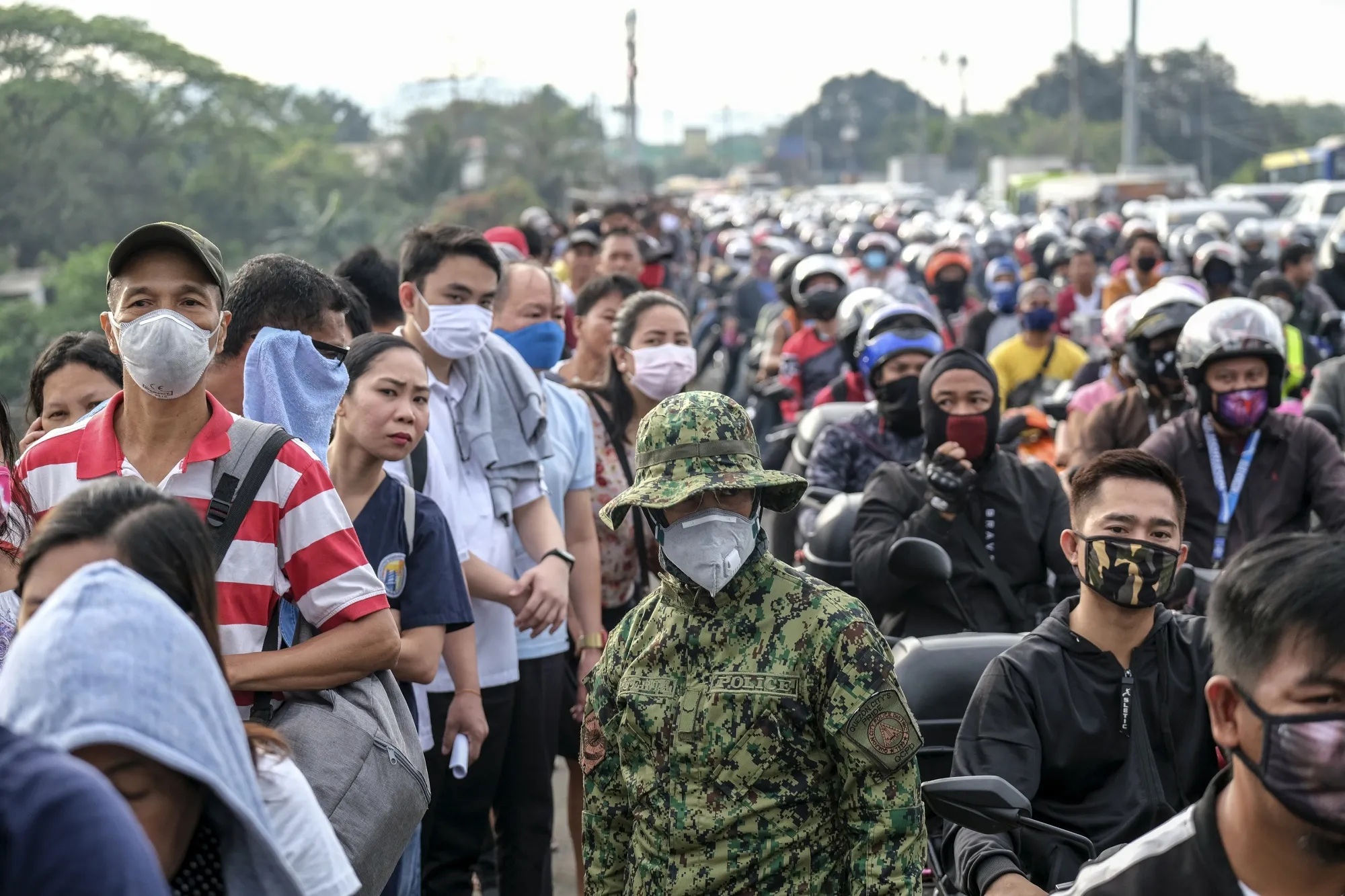 Commuters and motorists traveling into Metro Manila wait in line to pass through a check point in Quezon City, Metro Manila, March 16.