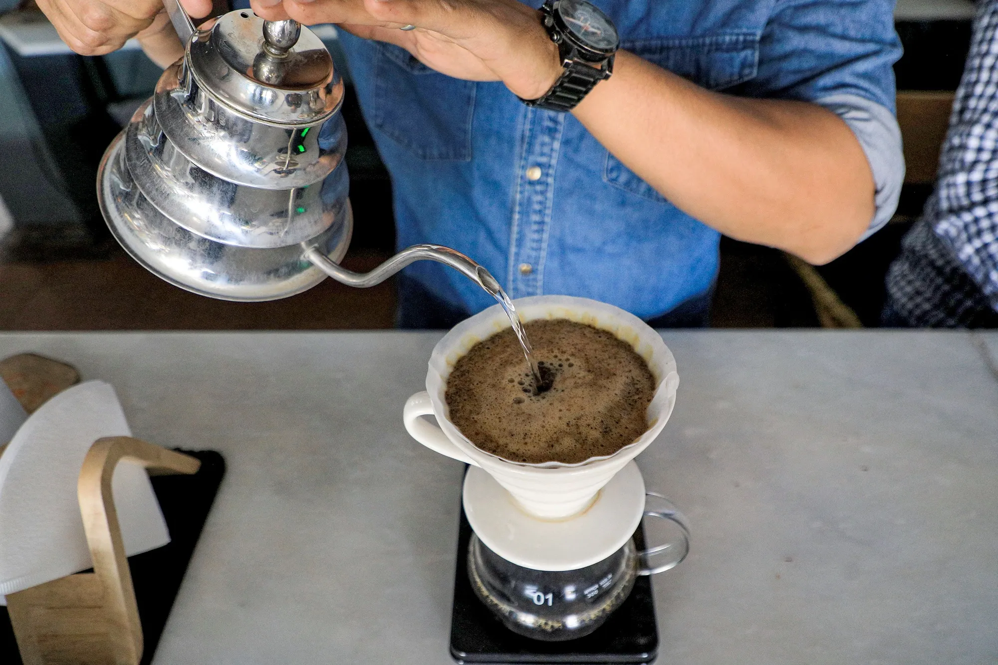 A speciality coffee shop employee serves filtered coffee.