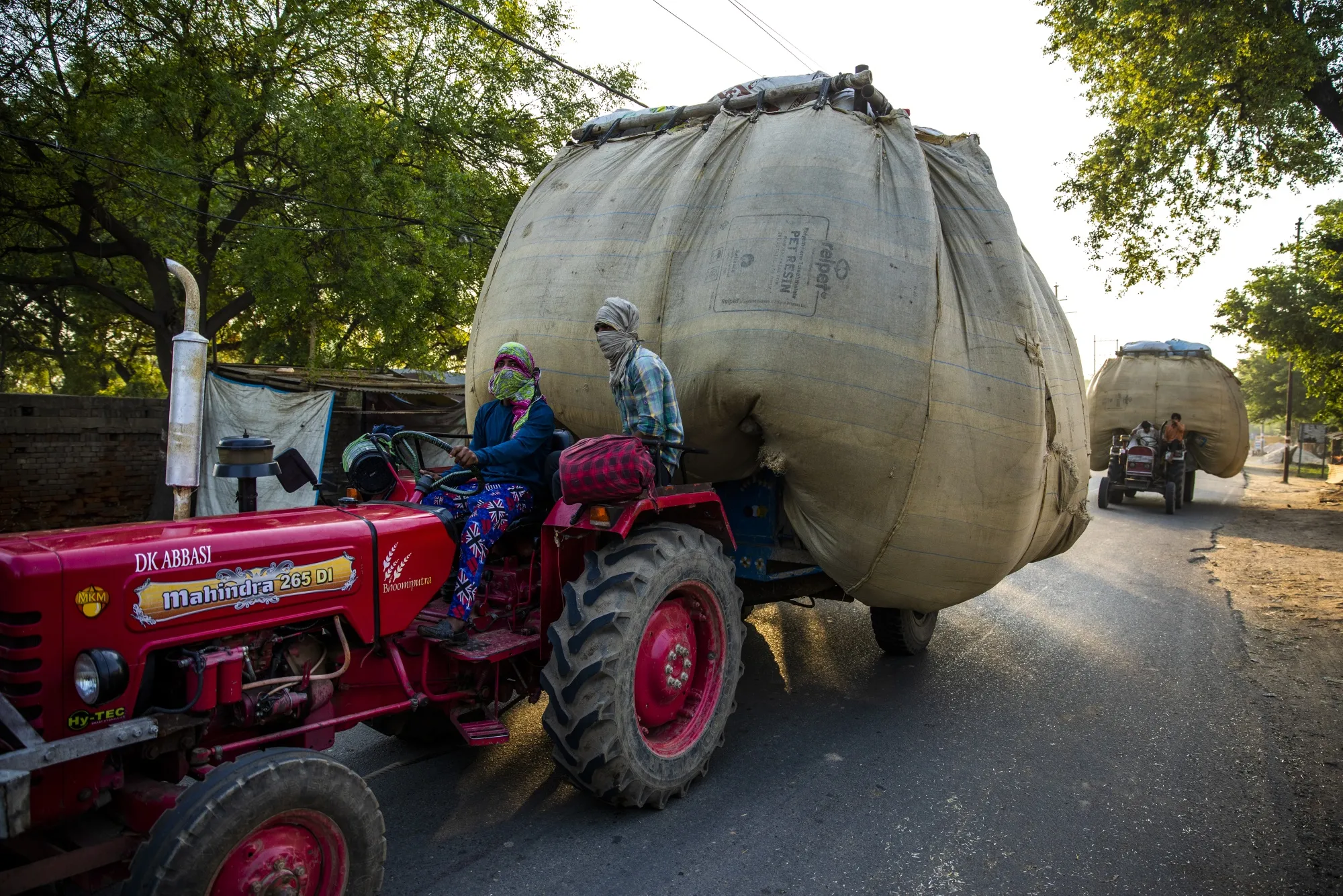 Farmers transporting wheat husk by tractor travel along a road&nbsp;in the Bulandshahr district of Uttar Pradesh, India.
