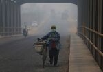 A woman pushes a bicycle as haze shrouds a street in the Indonesian island of Sumatra.