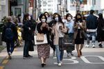 People wearing protective masks walk through the Garosu-gil neighborhood of the Gangnam district in Seoul on April 18.