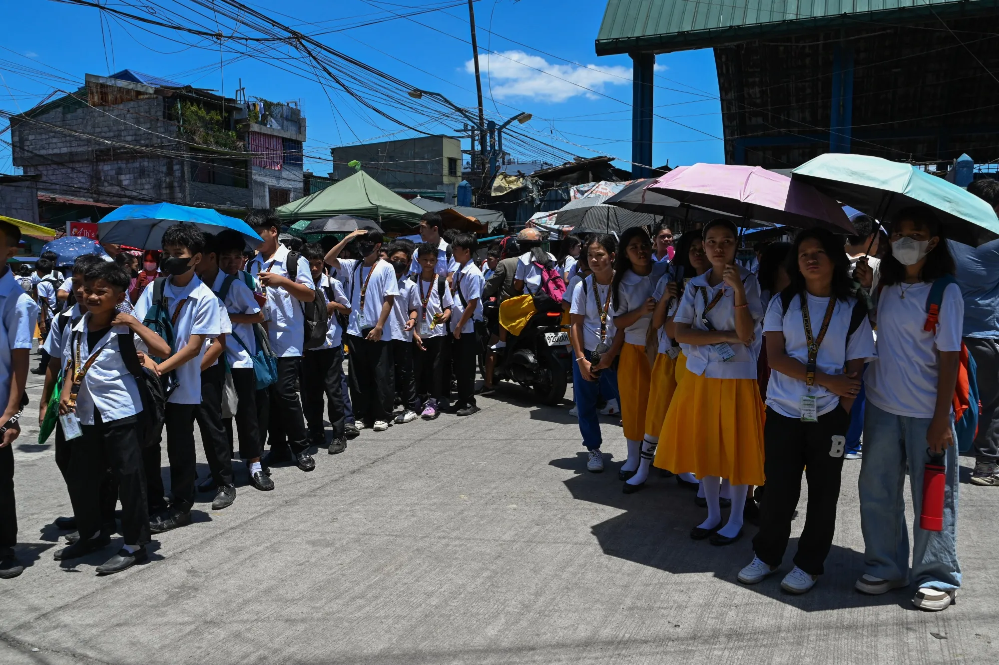 Students use umbrellas to protect themselves from the sun as they wait outside school in Manila, on April 2.