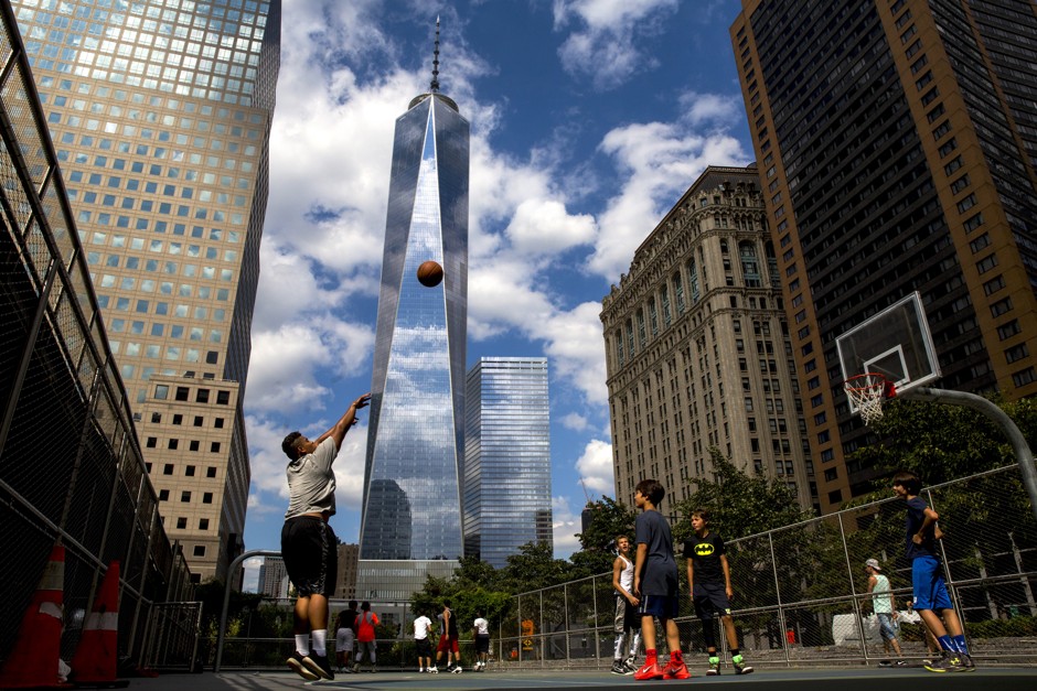 One World Trade Center looms over lower Manhattan as children play basketball. 