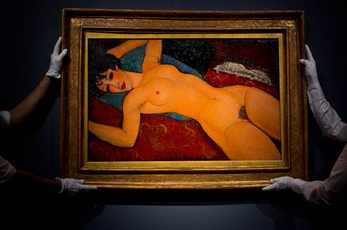 Art handlers hang the painting 'Nu couche' by artist Amedeo Modigliani.