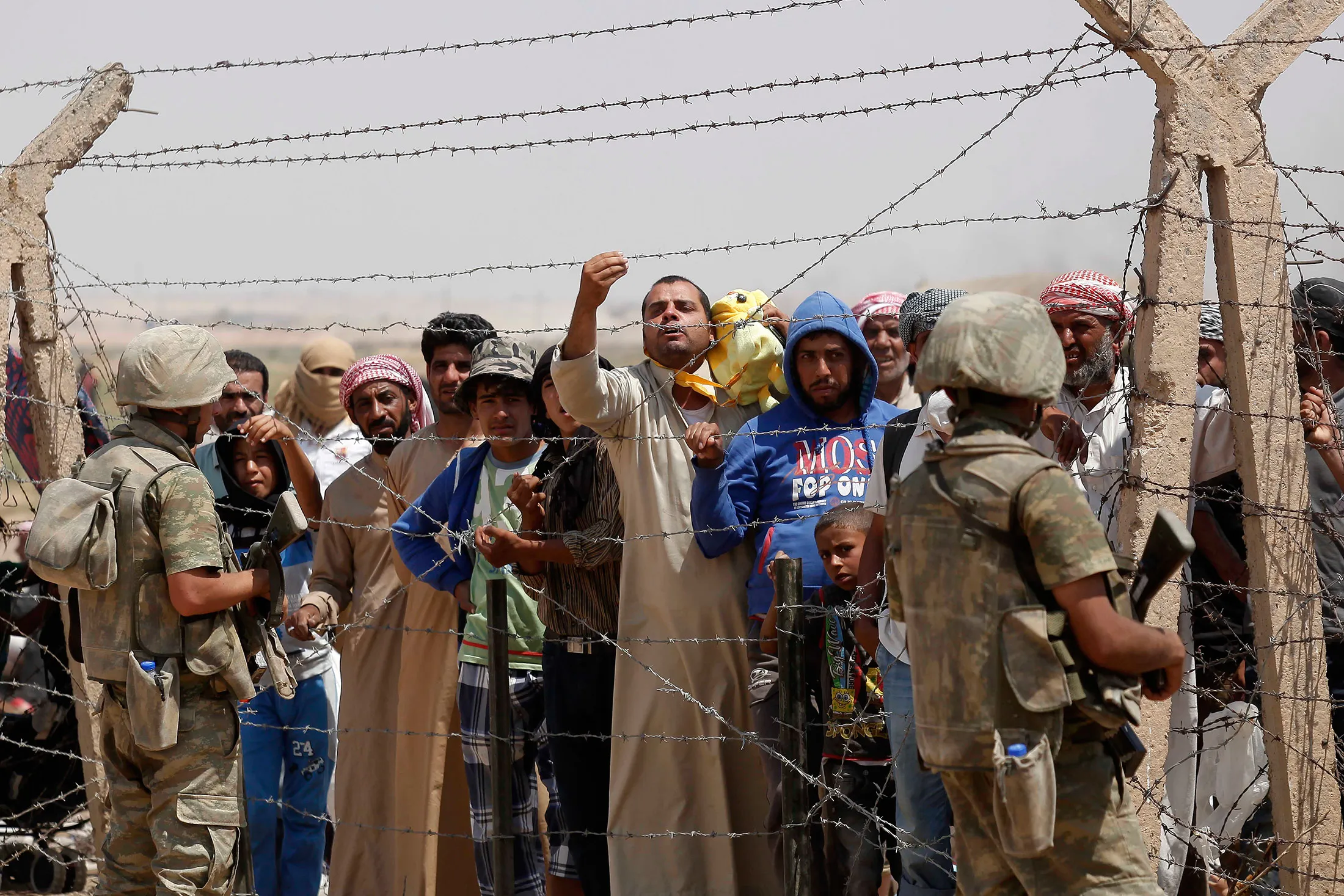 Syrian refugees wait on the Syrian side of the border to cross Akcakale, on June 15, 2015 in Sanliurfa province, southeastern Turkey. Thousands of Syrians cut through a border fence and crossed over into Turkey on Sunday, fleeing intense fighting in northern Syria between Kurdish fighters and jihadis.
