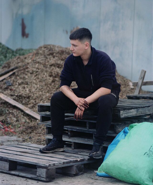 A young worker outside a mill in Nemea during the harvest season, his hands stained black from handling olives.