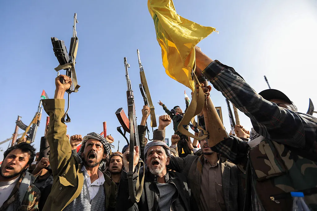 Supporters of the Houthi movement in Yemen raise their rifles during a rally in Sanaa