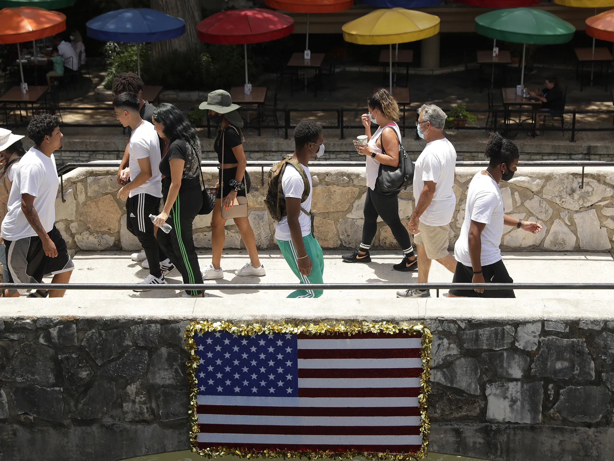 Visitors to the River Walk, some wearing masks to protect against the spread of the novel coronavirus, cross a bridge in San Antonio on June 24.