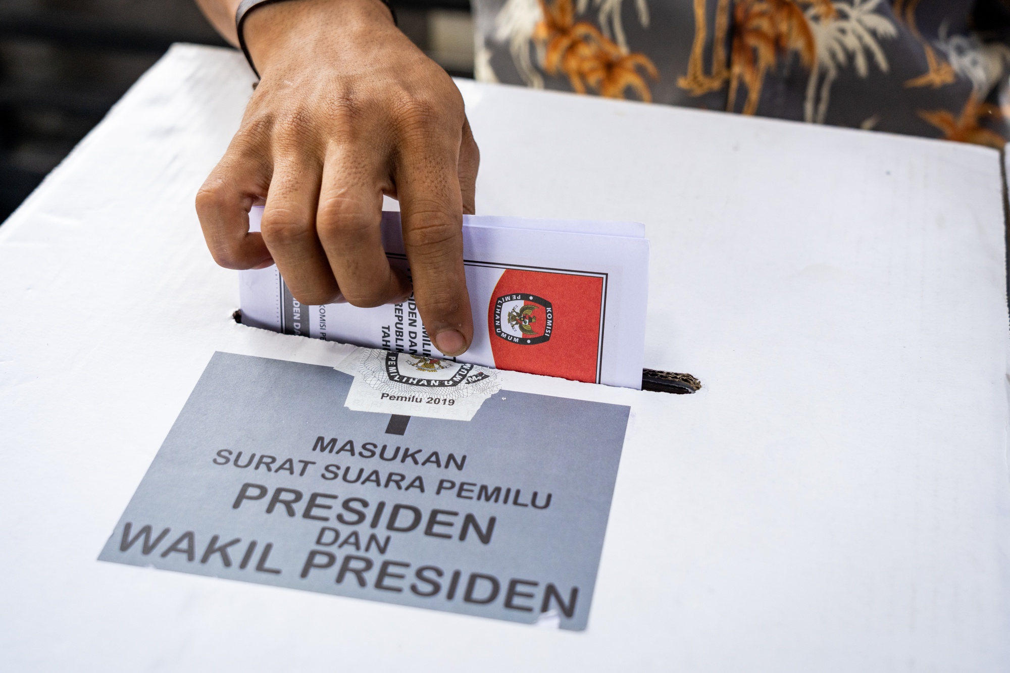 An election official deposits a voter's ballot into a box at a polling station during the general election in Bogor, West Java, Indonesia.