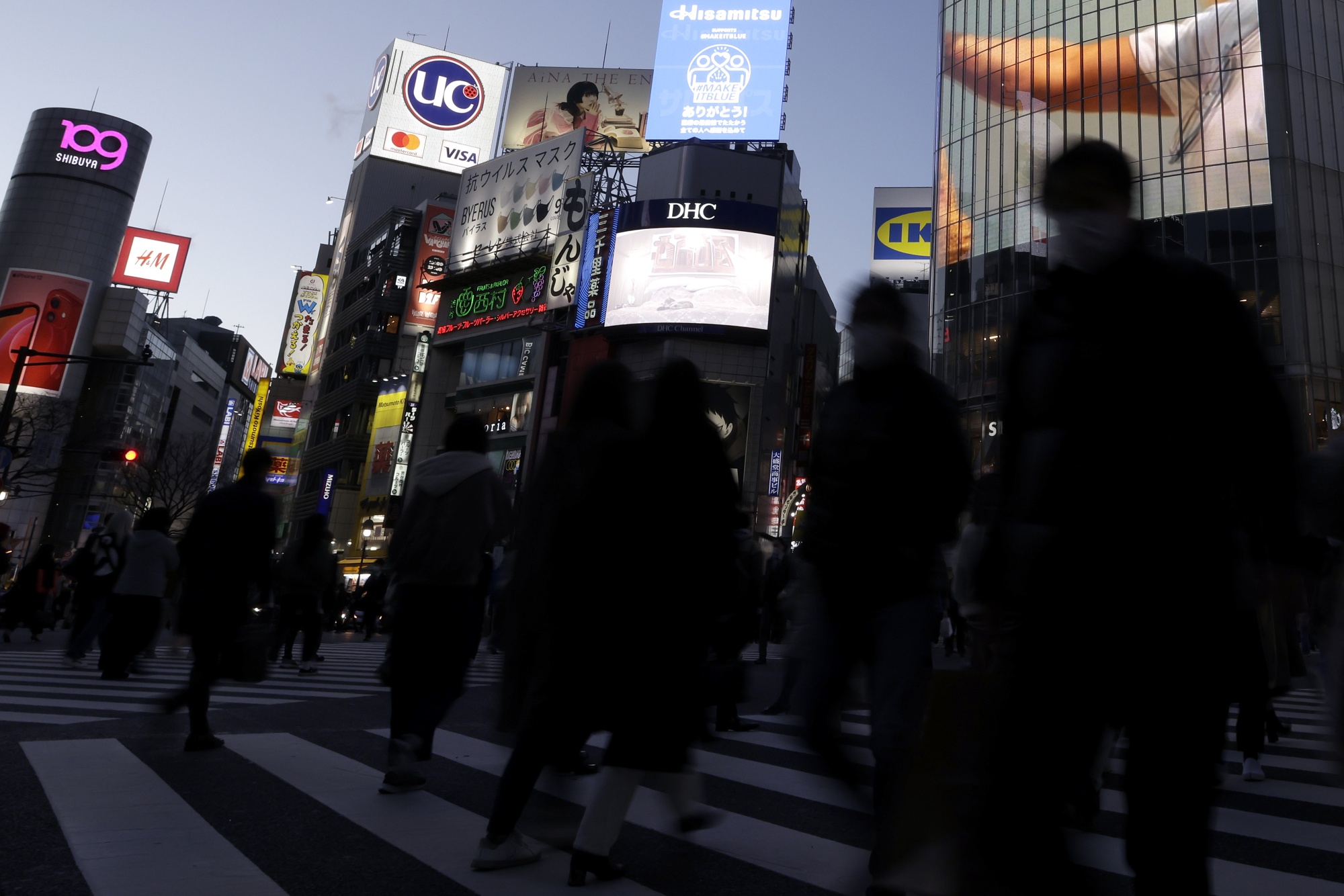 Pedestrians cross an intersection at dusk in the Shibuya district of Tokyo, Japan, on Wednesday, February 17, 2021. Bank of Japan Governor Haruhiko Kuroda says it will be difficult for the bank to reach its price target even in 2023, hinting that he needs to maintain monetary easing long after his current term ends.