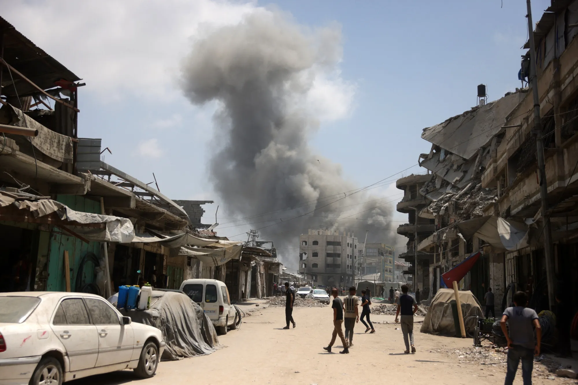 Palestinians watch as a plume of smoke rises during an Israeli strike on Gaza City on Aug. 8.