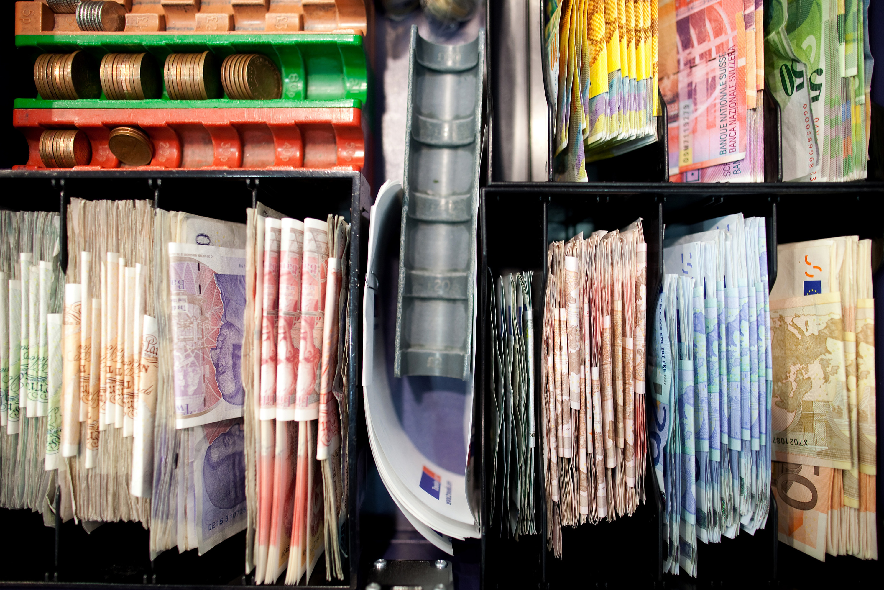 Mixed denomination currency banknotes, including euros, bottom right, and sterling, left, are seen in a cash register at a Travelex store in London.
