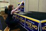 A woman places signs on a podium before an primary election watch party in Overland Park, Kansas.
