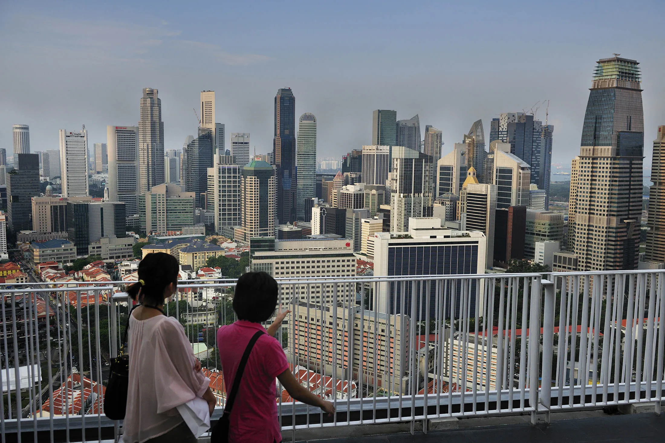 Visitors at the 50th floor skybridge of an apartment block take in a panoramic view of Singapore.
