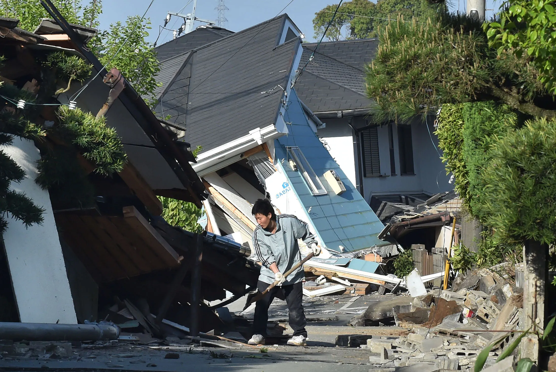 A man clears away debris of a broken wall following an earthquake in Mashiki, Kumamoto prefecture on April 16, 2016.
