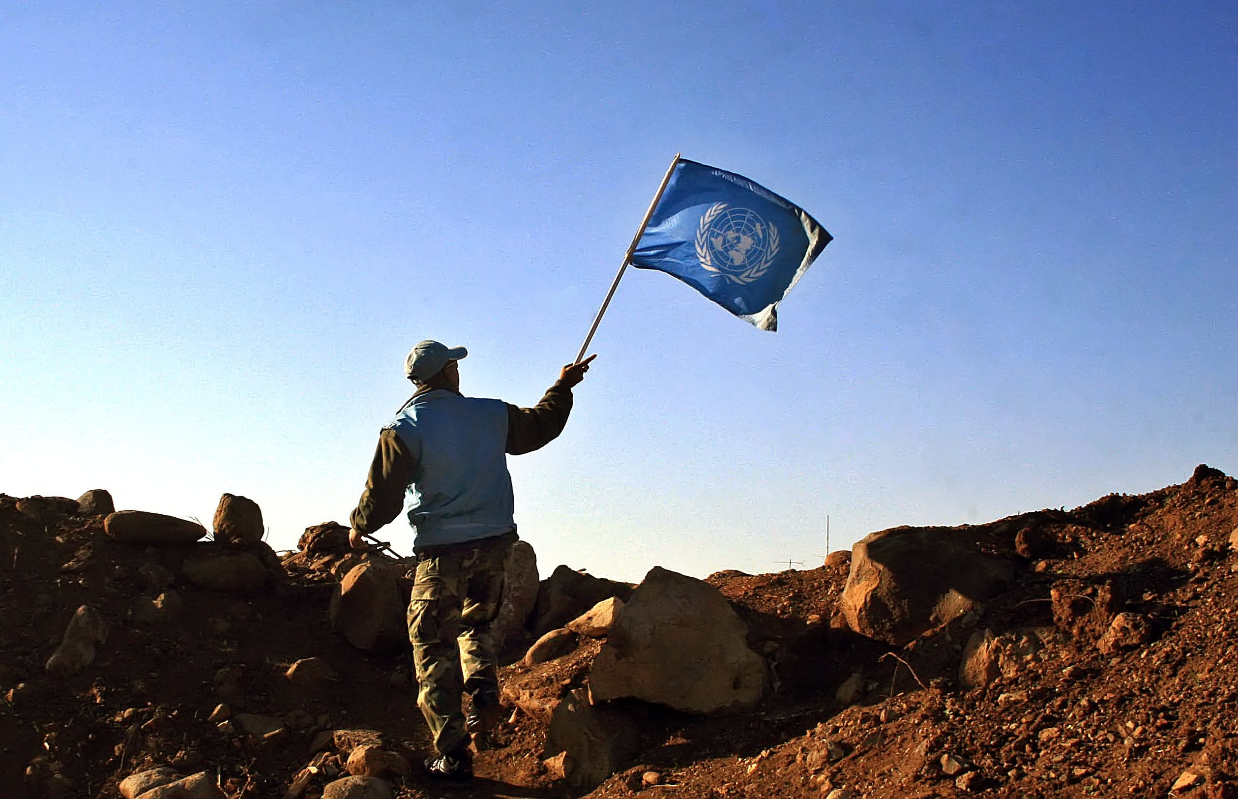 A UN Indian soldier waves the UN flag at the outskirts of the Lebanese village of al-Ghajar in 2006. Photo by ALI DIA/AFP via Getty Images.
