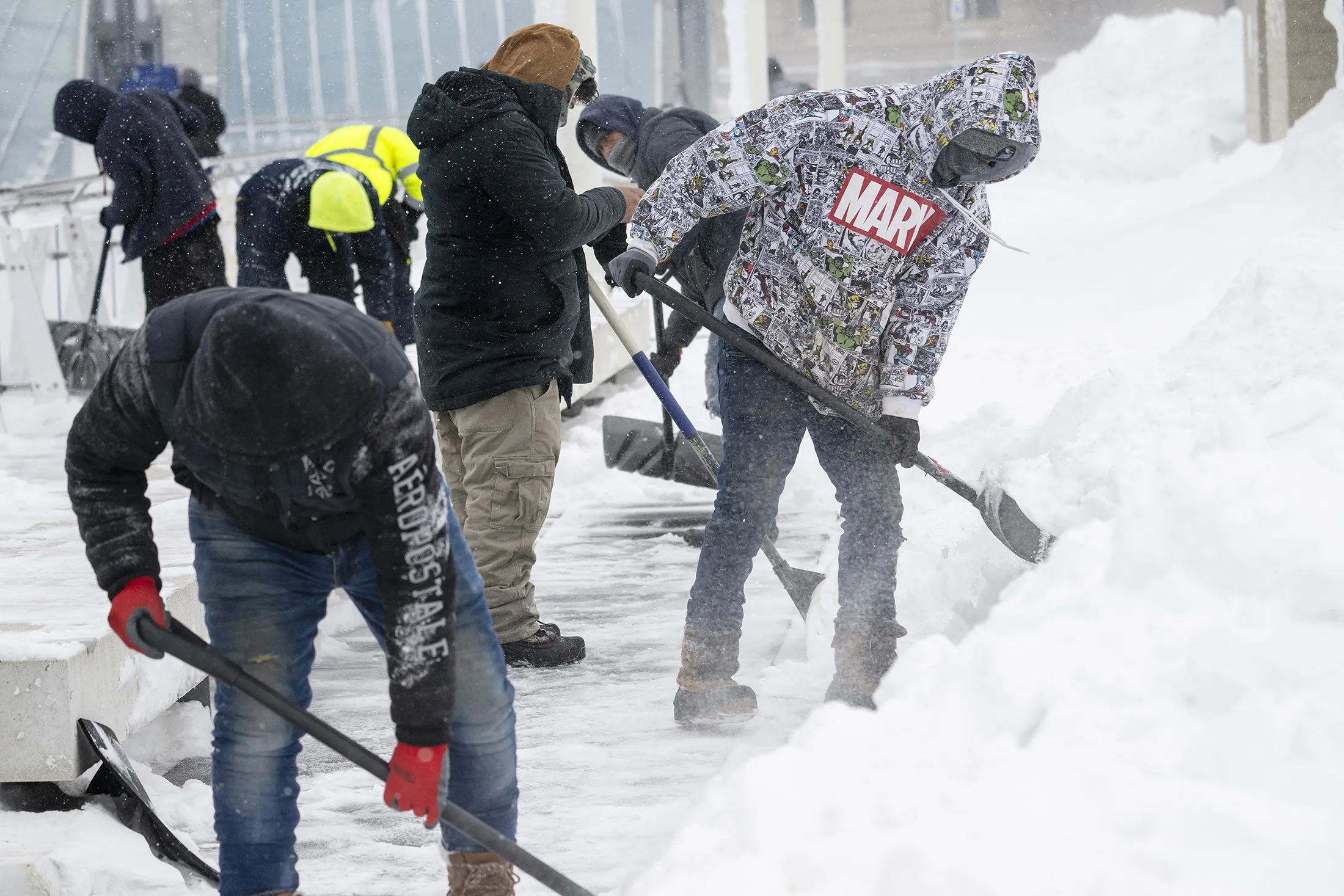 Workers clear a sidewalk of snow in Des Moines, Iowa, on Jan. 13, 2024.