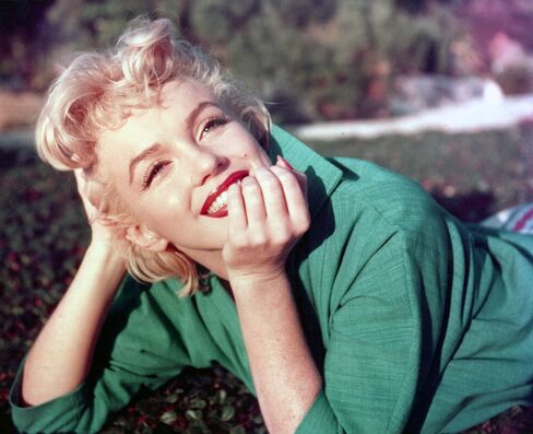 Actress Marilyn Monroe poses for a portrait as she lies on the grass in 1954 in Palm Springs, Calif.