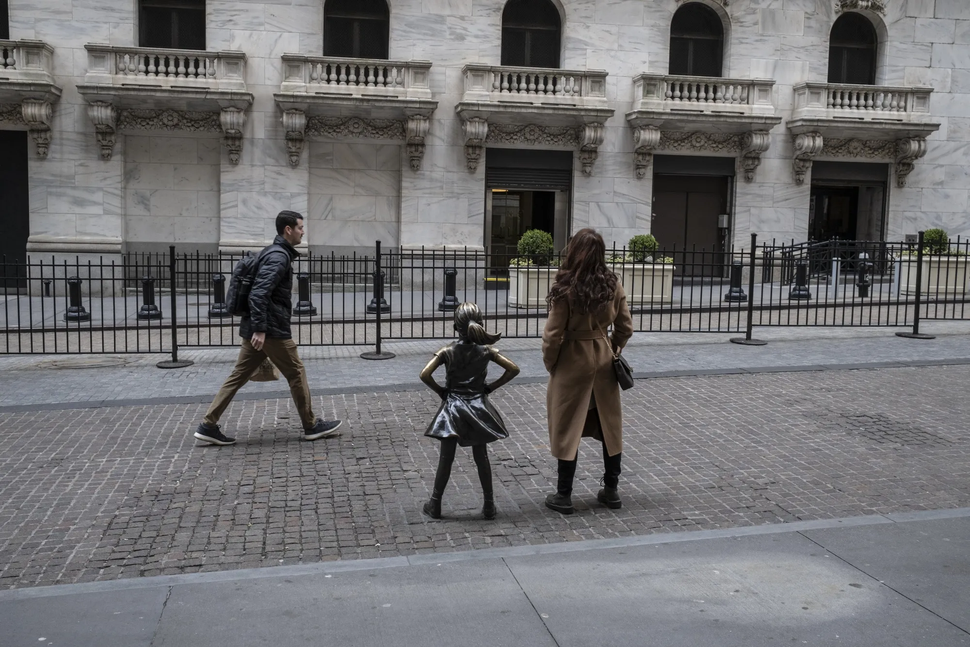 A visitor poses next to the 'Fearless Girl' statue outside the New York Stock Exchange (NYSE) in New York, US, on Tuesday, March 28, 2023.&nbsp;