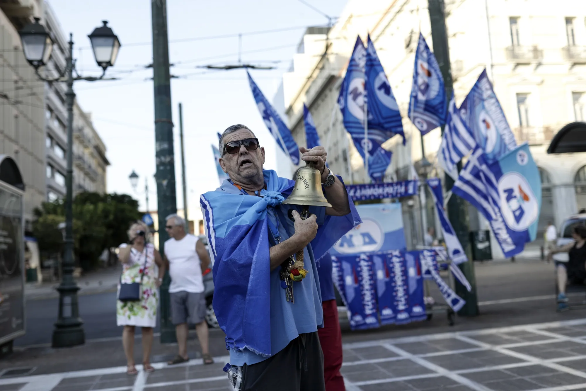 A supporter rings a bell while watching exit poll results at the New Democracy party election stand in Athens, Greece on Sunday, July 7 2019.