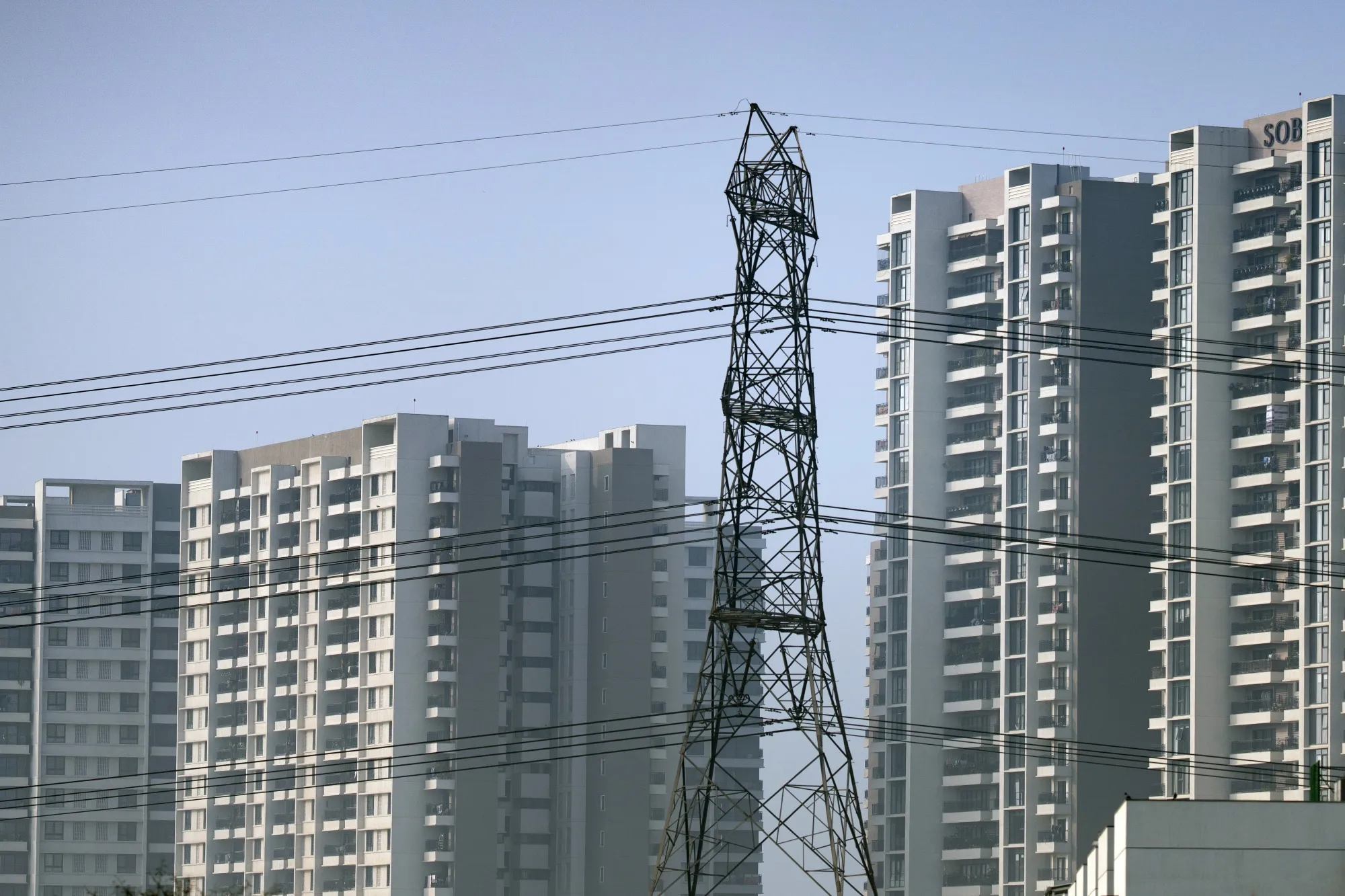An electricity pylon in front of residential buildings in New Delhi, India.