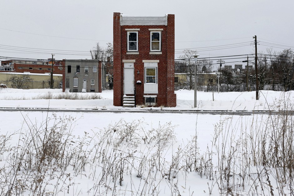 A lone Baltimore rowhouse surrounded by vacant lots. Depopulation has left the city with an excess of such spaces.