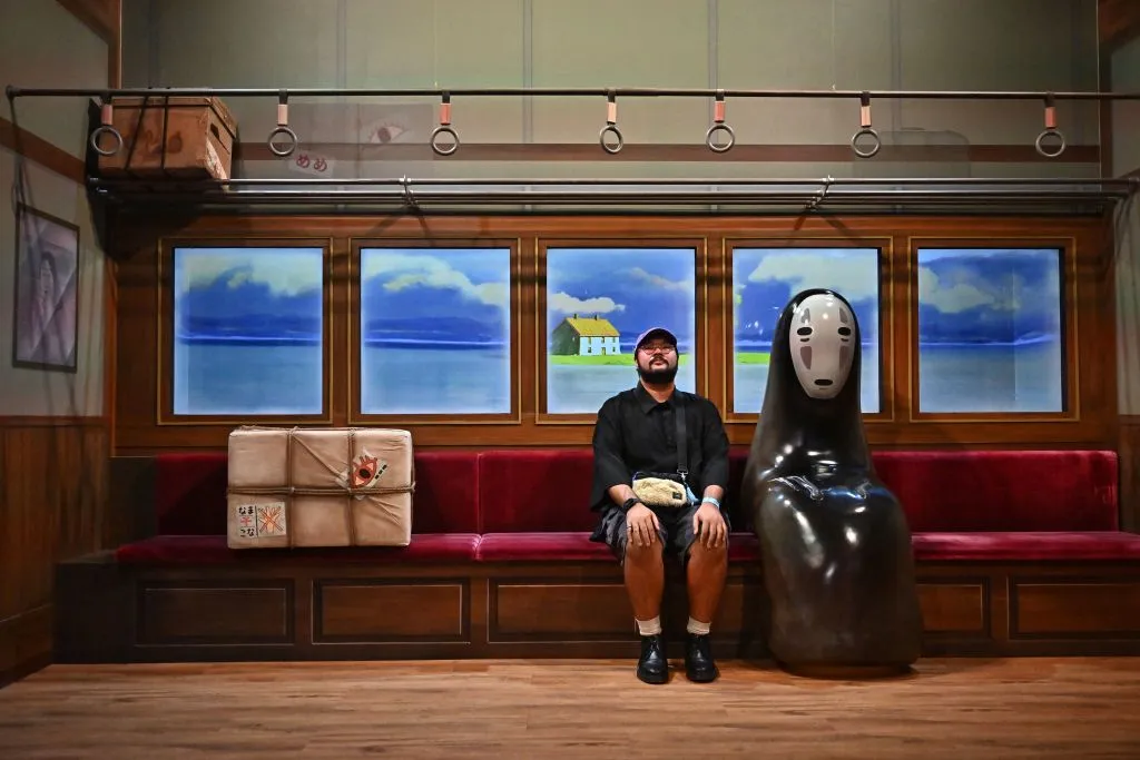 A man sits next to&nbsp;“No-Face,” a character from the Studio Ghibli movie "Spirited Away."&nbsp;