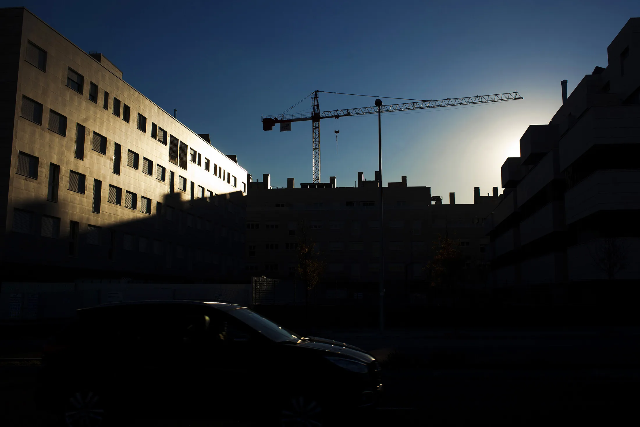 A construction crane operates above residential property in Madrid.
