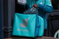 A Deliveroo courier collects an order from a restaurant in Soho, London