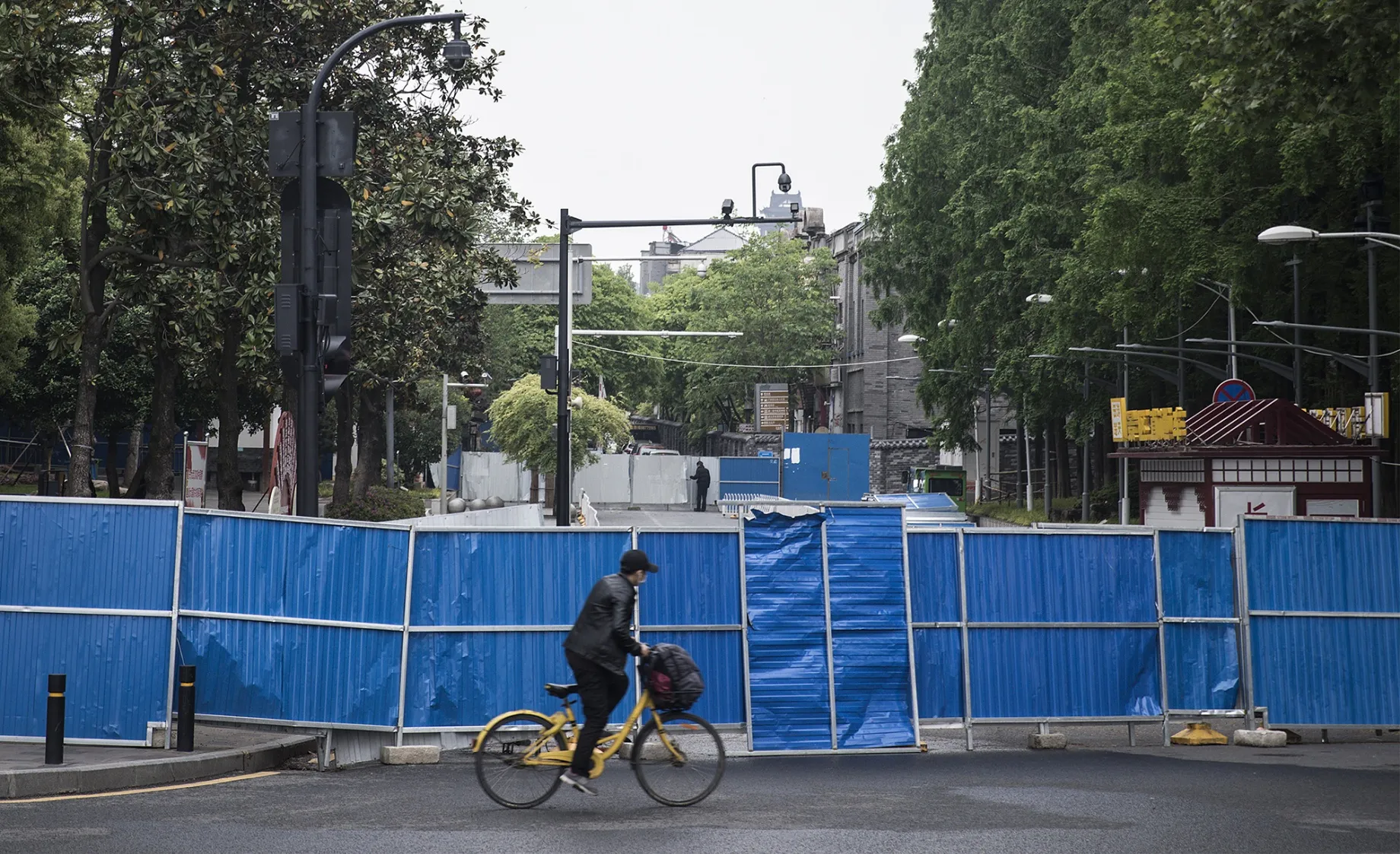 A man rides a bike past a barricade built to control entry and exit to a residential compound in Wuhan on April 21.