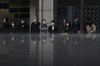 Pedestrians wait to cross a road in front of a monitor displaying stock information in Tokyo, Japan. 