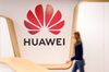 An employee walks past a logo in the reception area of the Huawei.