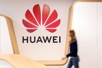 An employee walks past a logo in the reception area of the Huawei.